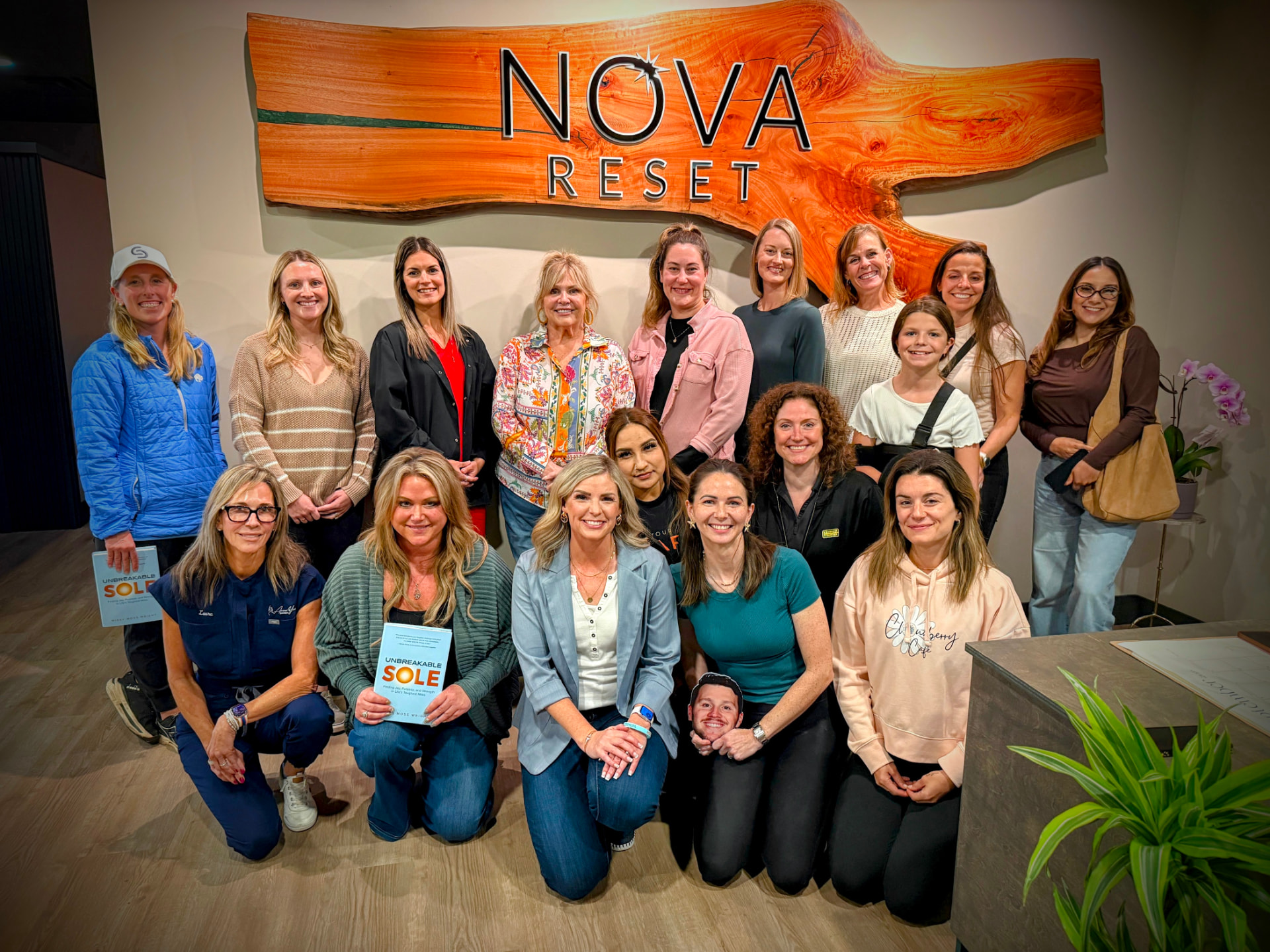 A group of NOVA guests smiling together in front of the NOVA RESET sign